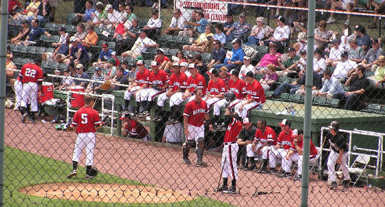 Players sit atop the dugout durng the game